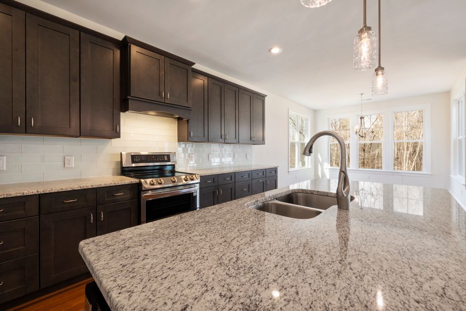 Spacious kitchen with granite island, dark wood cabinets, and large windows.